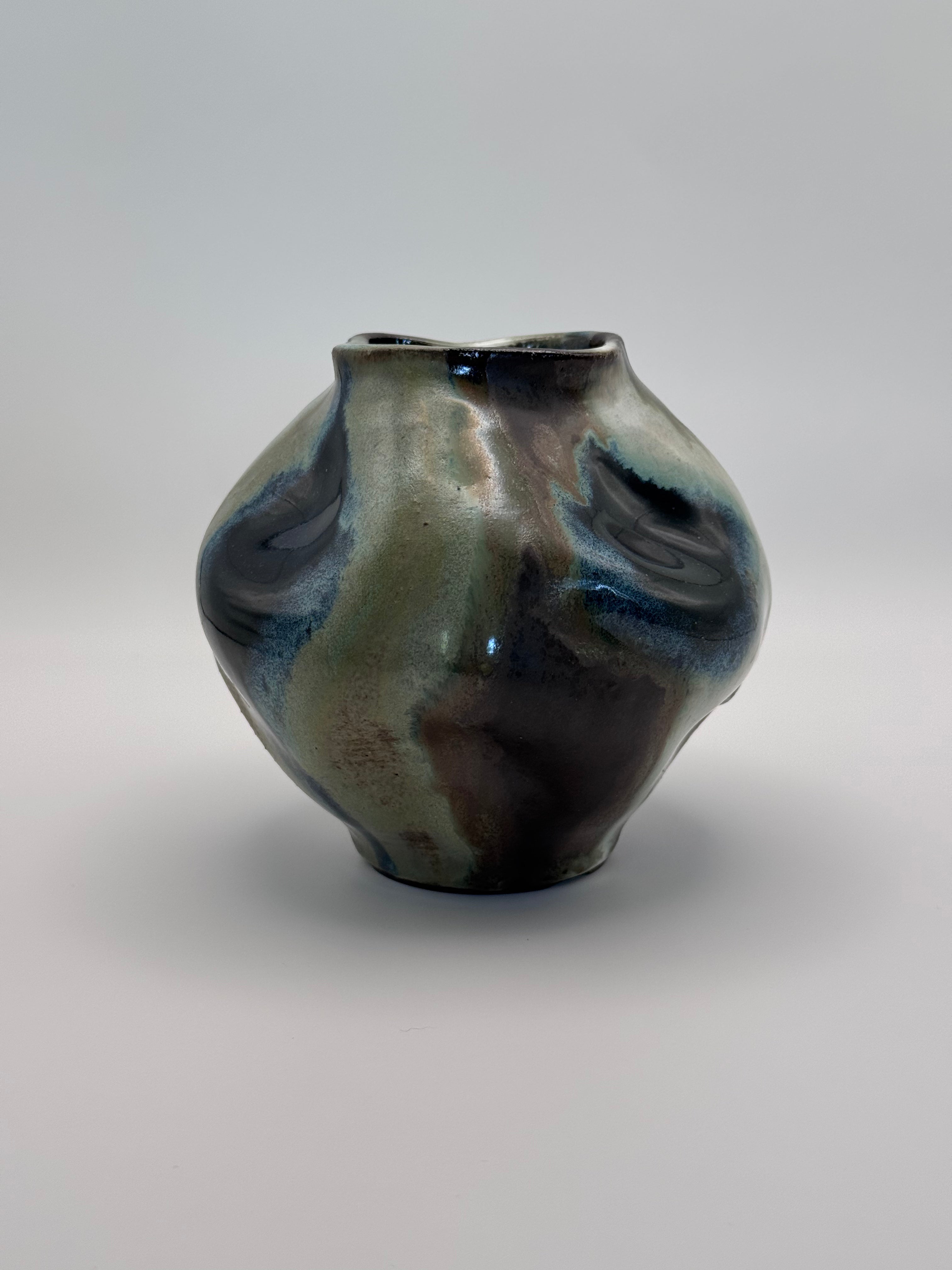 Hand-shaped ceramic vase with softly undulating walls and a wide mouth, marbled dark brown, white, green celadon, and light blue glaze.