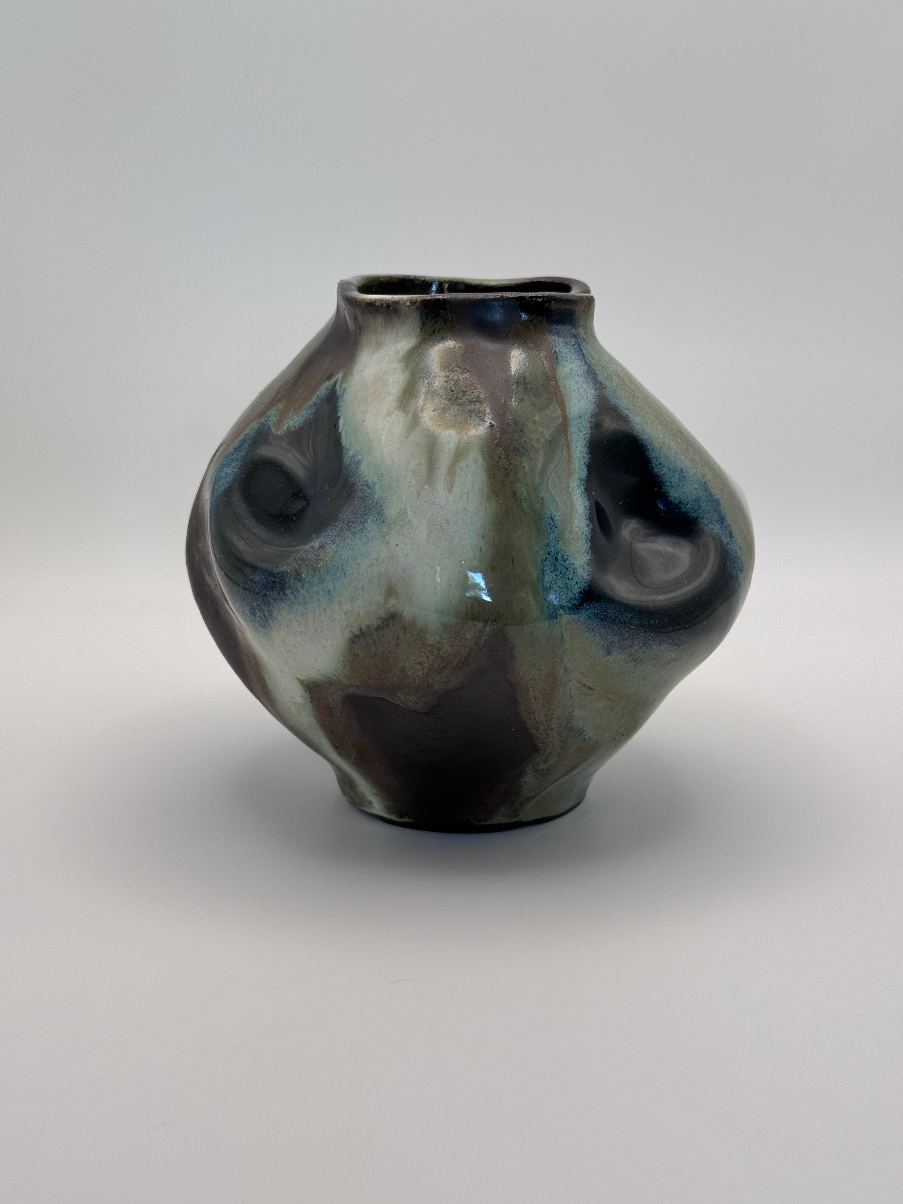 Hand-shaped ceramic vase with softly undulating walls and a wide mouth, marbled dark brown, white, green celadon, and light blue glaze.