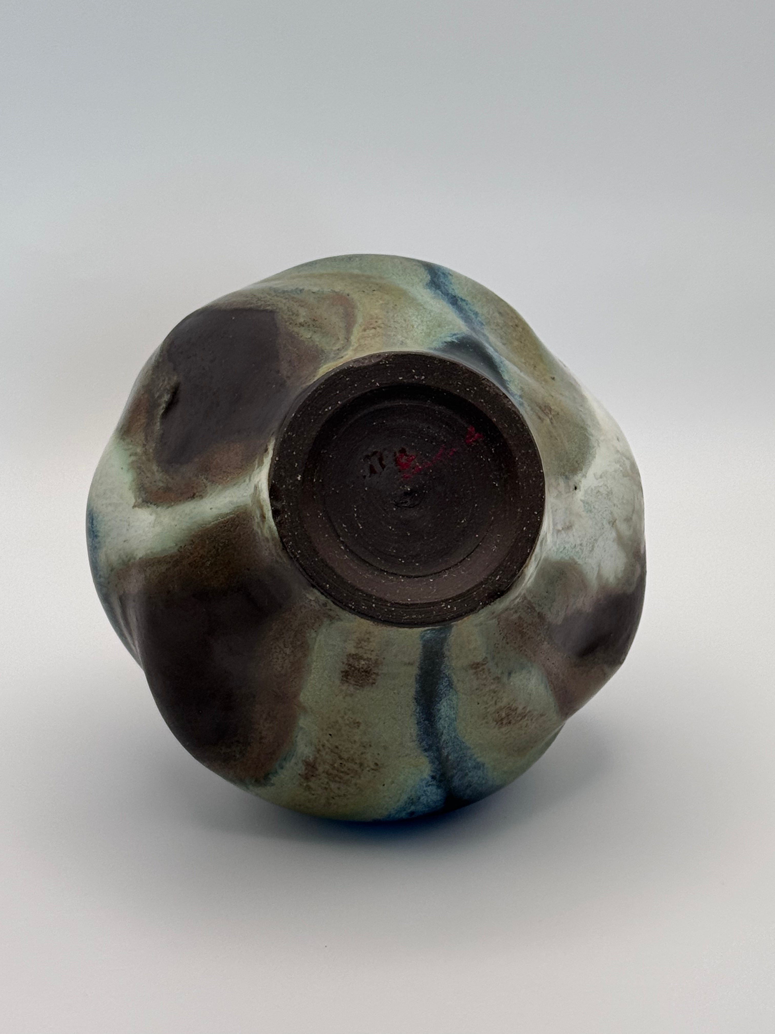 Foot of Hand-shaped ceramic vase with softly undulating walls and a wide mouth, marbled dark brown, white, green celadon, and light blue glaze.