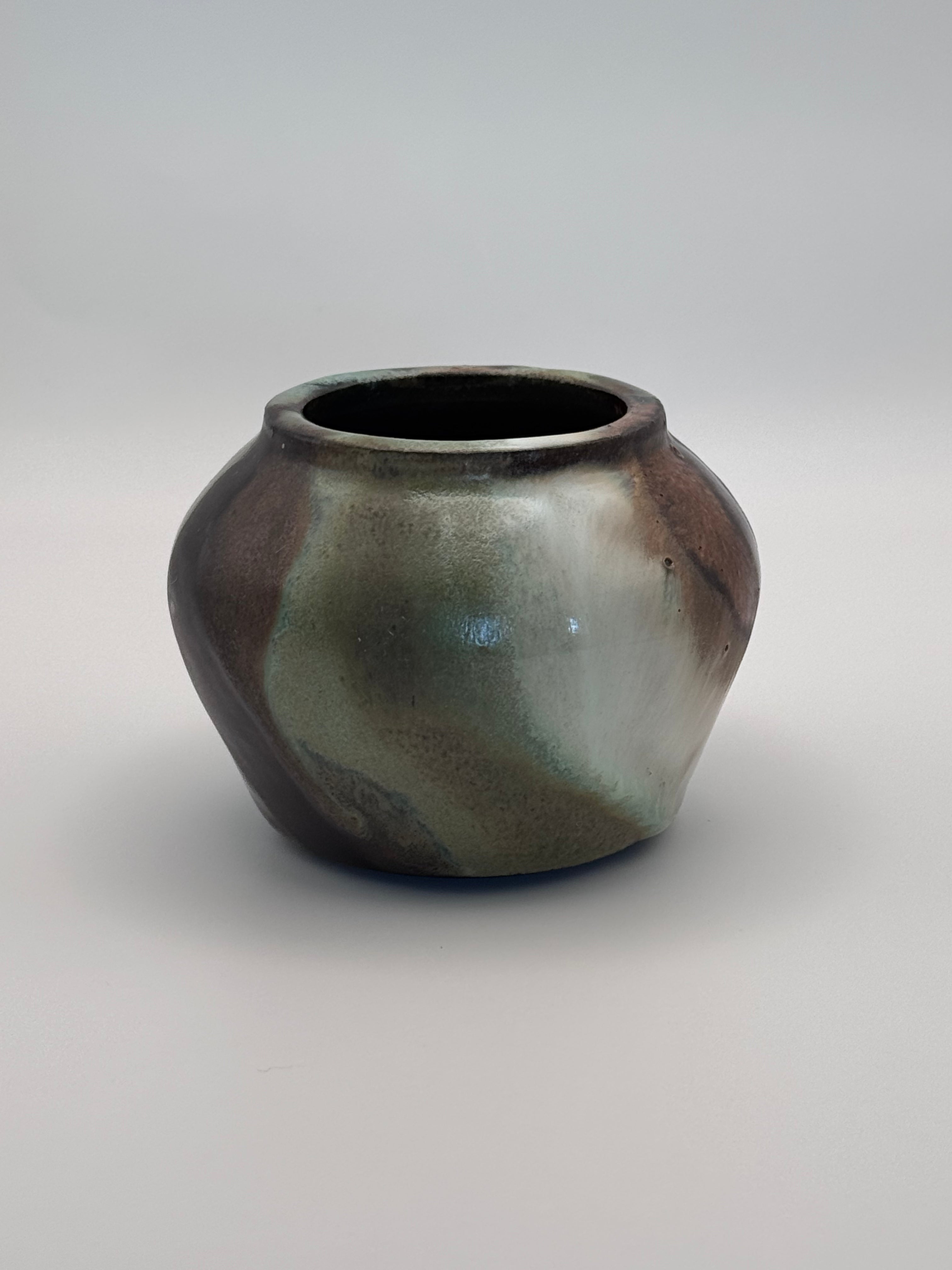 Small ceramic bud vase with rounded shoulders, marbled dark brown, white, and green celadon glaze with metallic crystalline accents. View 1 of 4