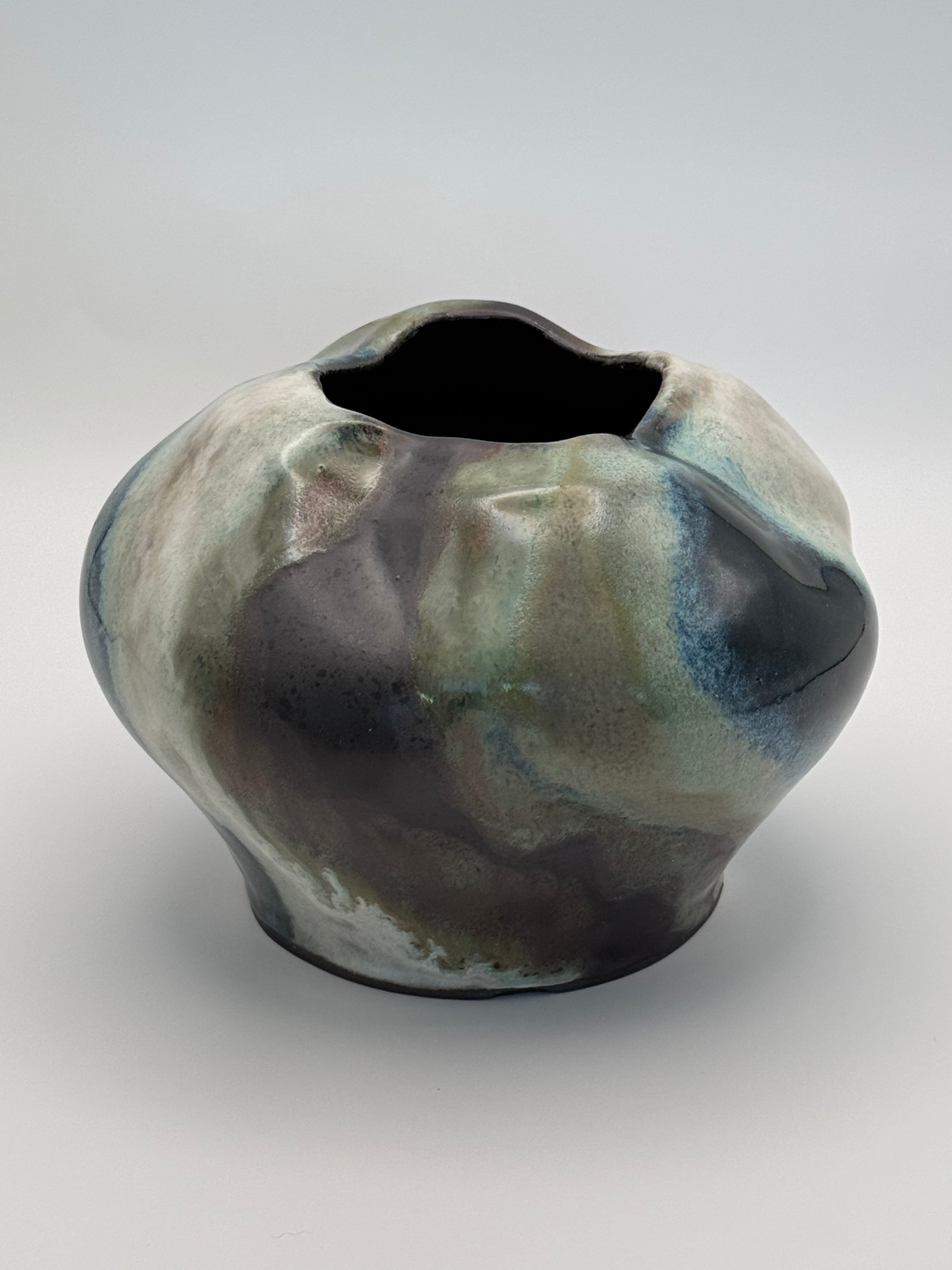 Ceramic vase with a full round body and irregular petal-like opening, marbled dark brown, white, green celadon, and light blue glaze. view 1 of 3