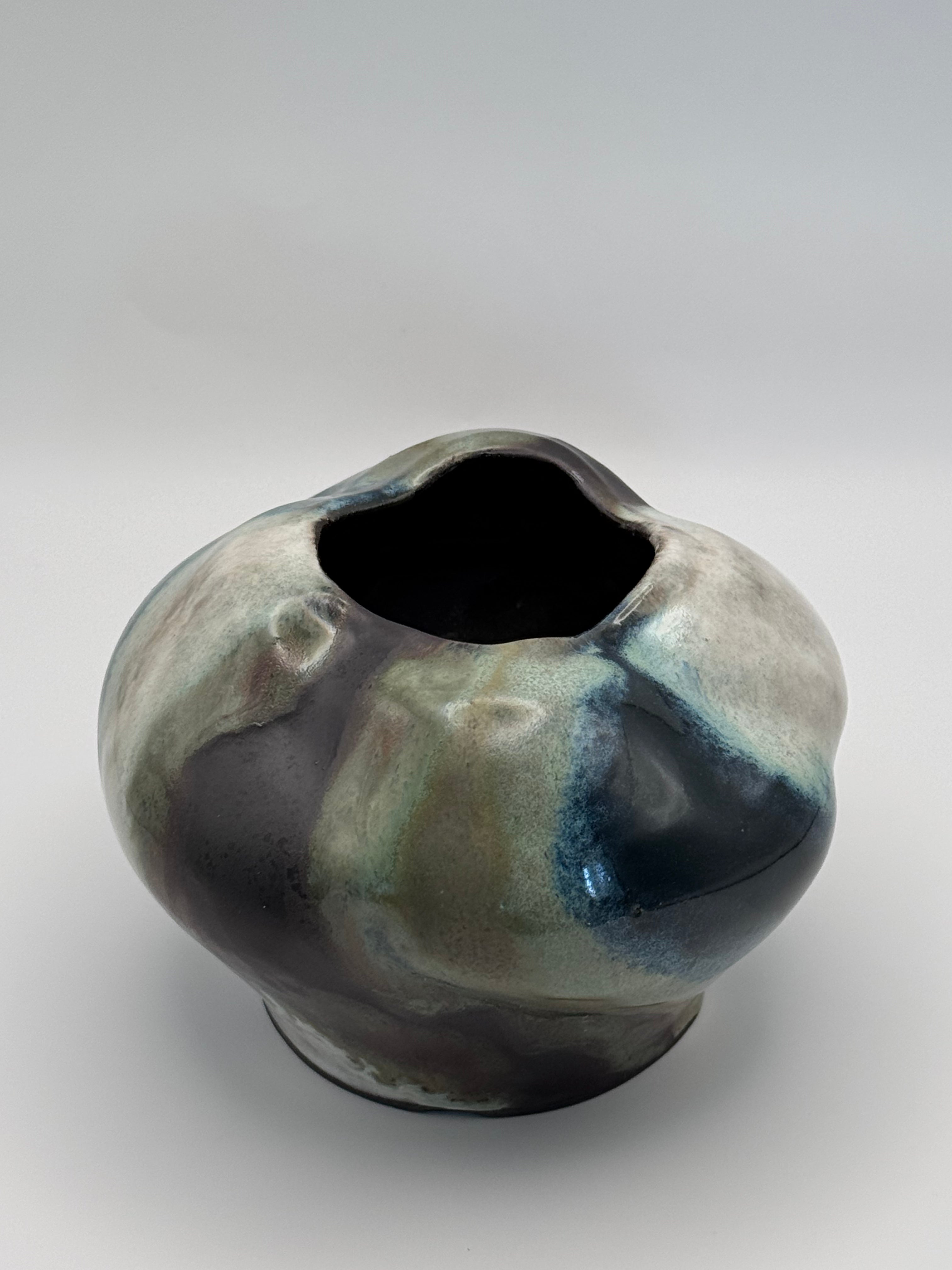 Top view of Ceramic vase with a full round body and irregular petal-like opening, marbled dark brown, white, green celadon, and light blue glaze.