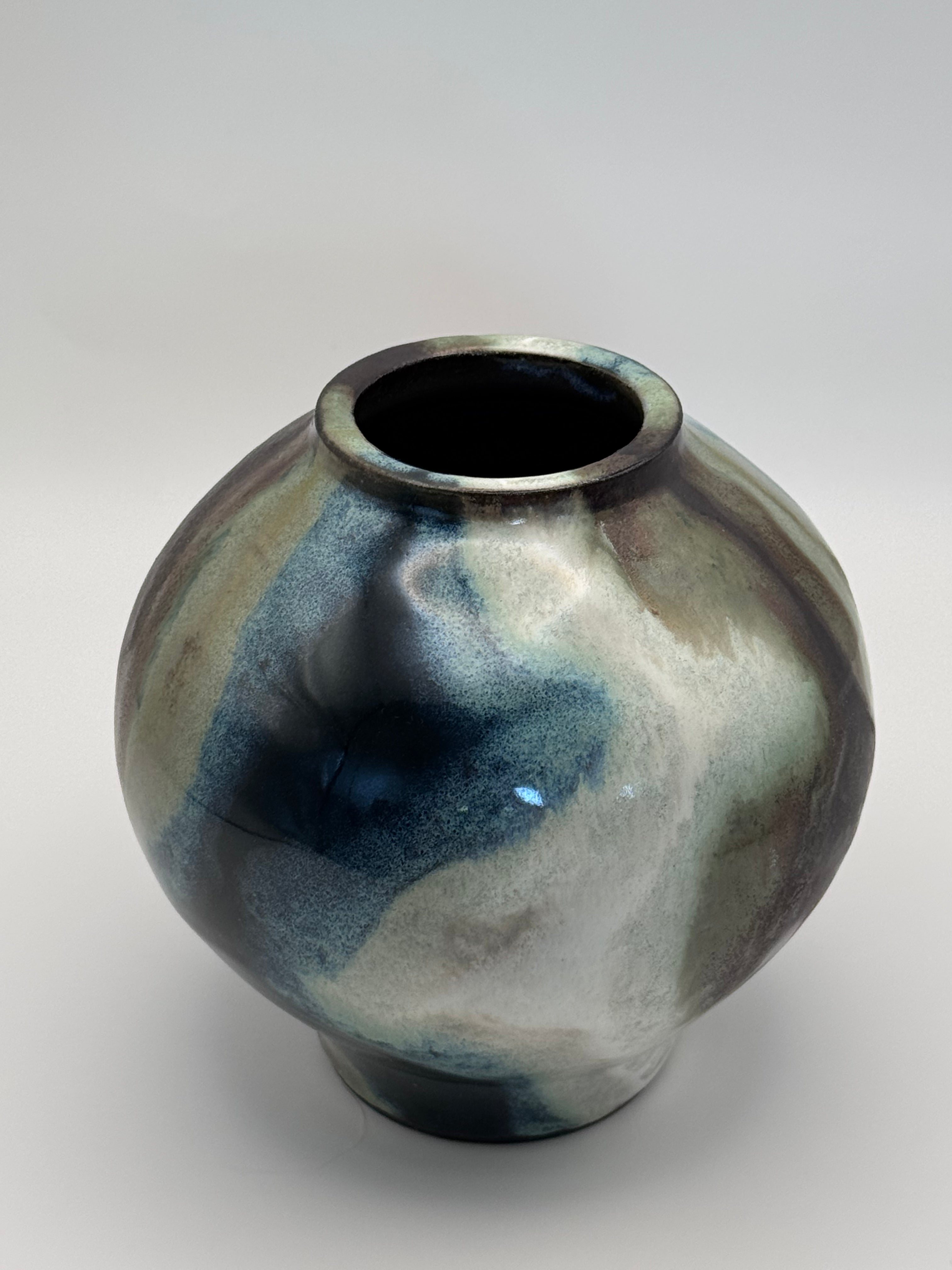 top view of Round ceramic vase with a narrow mouth, marbled dark brown, white, green celadon, and light blue glaze.