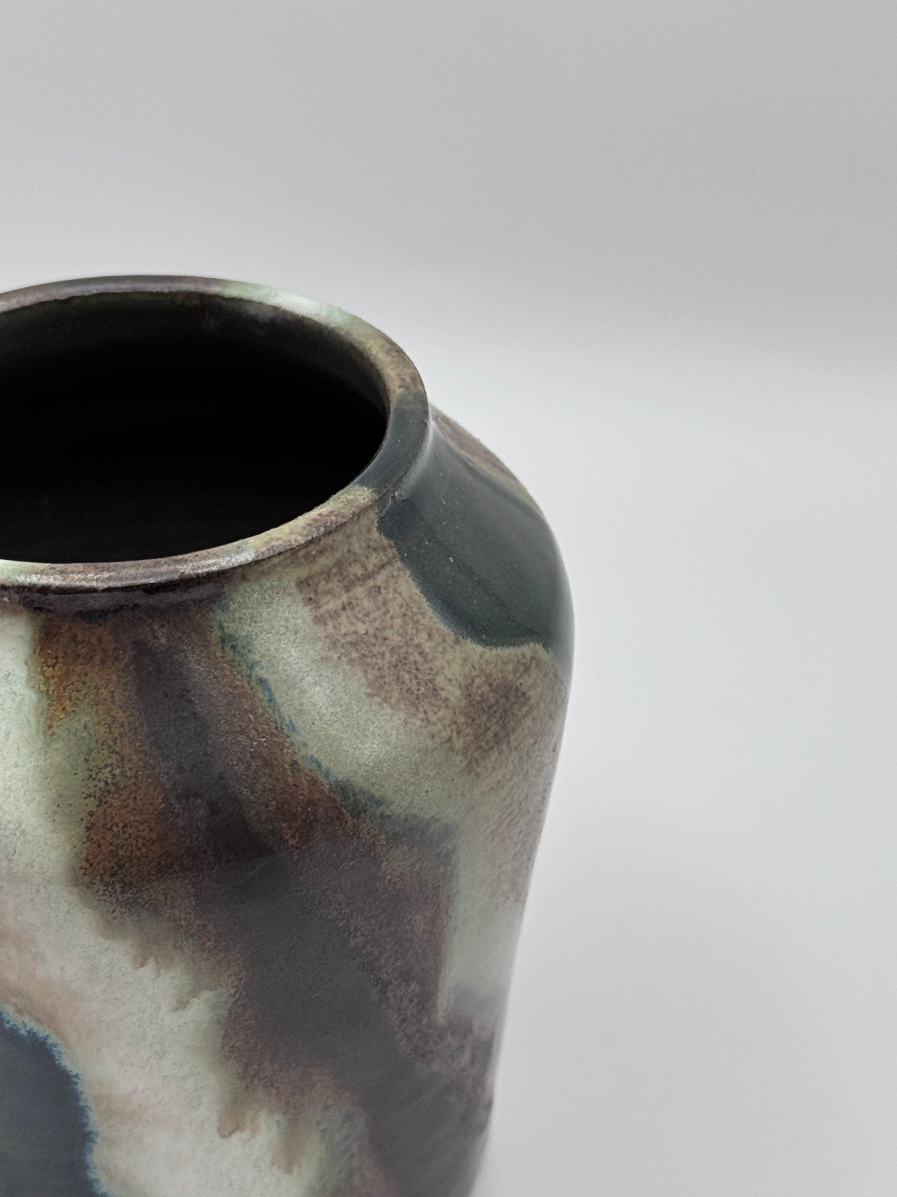 Close up view of tall ceramic vase with a defined shoulder and wide mouth.